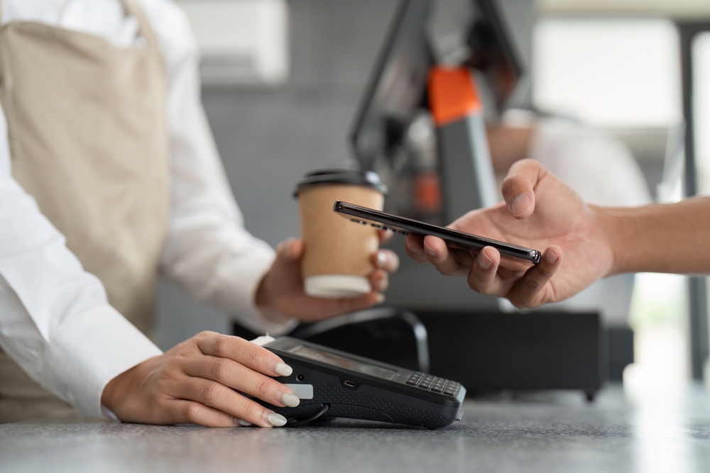 カフェで飲食店の定額サービスをスマートフォンで確認する日本人男性