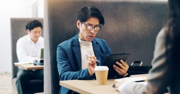 飲食店の開業資金について調べながら、カフェでタブレットを操作する日本人男性