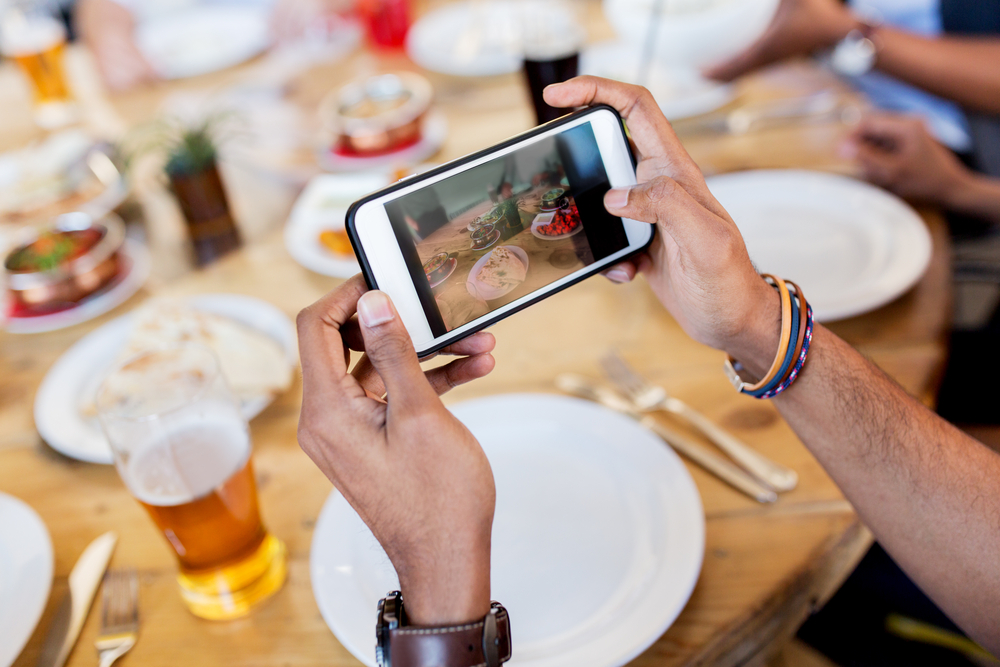 レストランの料理をスマートフォンで撮影する手元